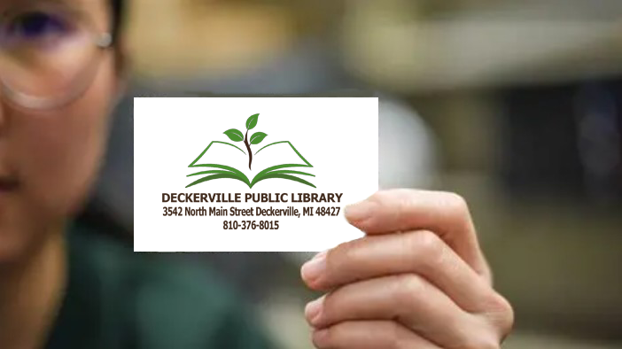 hand holding a library card to sign up call 810-376-8015
